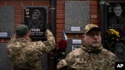 A colleague hangs a memorial picture on the grave of Ukrainian soldier Oleksandr Hrianyk in Kyiv, Ukraine, Oct. 28, 2023. Hrianyk died in battle in May 2022 in the city of Mariupol but was only cremated recently after his remains were found and identified.