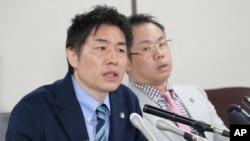 Lawyers of a claimant, Kazuyuki Minami, left, and Masafumi Yoshida, right, speak to media after the ruling of the Supreme Court, Oct. 25, 2023, in Tokyo.