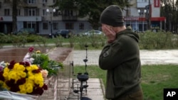 A servicewomen cries as she lays flowers to commemorate those killed in the war, as the city marks one year since Ukraine retook the city of Kherson from occupying Russian forces in Kherson, Ukraine, Nov. 11, 2023.