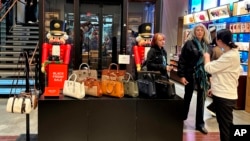 Shoppers pause near a display of handbags at a Coach store in New York on Nov. 19, 2023.