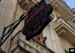 A resident looks out from her balcony over a private grocery store in Havana on Nov. 11, 2023.