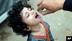 A health worker administers a polio vaccine to a child in a neighborhood of Lahore, Pakistan, Nov. 27, 2023.