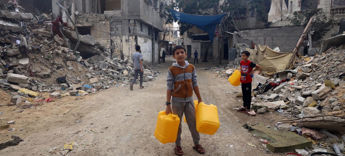 A boy collects water in a bombed neighbourhood in Gaza. 