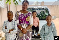 Pascazia Mazeze, executive director of the Tanzania Sickle Cell Warriors Organization, is pictured with her sons, Ian, Rian and Gian, at their home in Tanzania, April 9, 2023. Ian, who has sickle cell disease, takes hydroxyurea and folic acid for anemia.