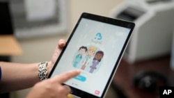 An employee of Hazel Health displays the opening page of the company's app, which allows Miami-Dade County public school students to receive telehealth therapy services, on World Mental Health Day, Oct. 10, 2023, at Miami Arts Studio, a public 6th-12th grade magnet school.