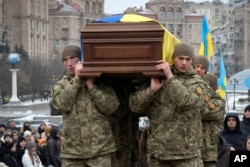 Ukrainian serviceman carry a coffin bearing Ukrainian poet Maksym Kryvtsov at St. Michael Cathedral in Kyiv, Ukraine, Jan. 11, 2024.