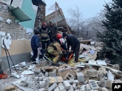Rescuers help a wounded person after residential houses were destroyed by a Russian missile attack, in Novomoskovsk, near Kryvyi Rih, Ukraine, Jan. 8, 2024. (Ukrainian Emergency Service via AP)