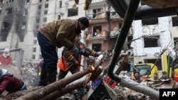 Utility workers repair water pipes outside a high-rise building destroyed in a Russian missile attack in central Kyiv, Ukraine, Jan. 3, 2024.