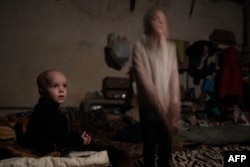 FILE - Sasha, 4, and his sister Ksenia, 8, pose in a bedroom in the basement shelter in Lysychansk, eastern Ukraine, on May 15, 2022, amid the Russian invasion of Ukraine.