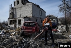 A local resident prepares a damaged car to be towed, near a residential building damaged during a Russian drone strike, amid Russia's attack on Ukraine, in Dnipro, Ukraine, Feb. 26, 2024.