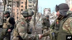 In this photo taken from video released by head of the Russian-controlled Donetsk region Denis Pushilin's telegram channel on Feb. 25, 2024, Denis Pushilin, head of the Russian-controlled Donetsk region, foreground left, greets a soldier in Avdiivka, eastern Ukraine.