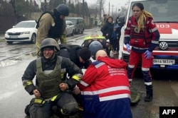 This handout photograph taken and released by Ukrainian Emergency Service on March 15, 2024 shows rescuers and medical staff providing assistance to an injured rescuer following a missile attack in Odesa, Ukraine.