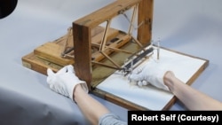 Photo illustrating how President Thomas Jefferson would likely have used the polygraph machine. The left pen in the right hand, the operator’s left hand on the paper retraction knob to pull fresh paper.