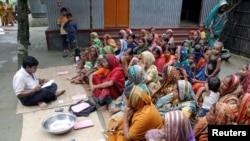 FILE - Bangladeshi women wait for a volunteer to distribute their loan money collected from a microfinance agency at Manikganj, 100 kilometers (62 miles) from the capital Dhaka, Sept. 24, 2005.