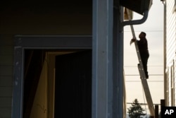 FILE - A worker stands on a ladder while working on a new construction home in Tigard, a suburb of Portland, Oregon, Feb. 22, 2024.
