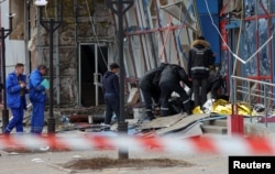 FILE - Specialists remove the body of a victim outside a heavily damaged shopping center hit by what local authorities called a Ukrainian military attack, in Belgorod, Russia, on Feb. 15, 2024.