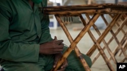 FILE - A worker tightens a bolt on a chair made out of bamboo at a factory in Wakiso, Uganda, on March 13, 2024.