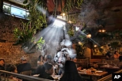 FILE - Patrons smoke marijuana at Lowell's Original Cannabis Cafe, a legal marijuana establishment, in Los Angeles, Nov. 13, 2019