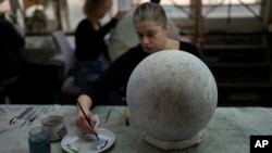 An artist paints a globe at a studio in London, Feb. 27, 2024.