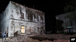 Police walk in front of a crater after a Russian rocket attack on a mental hospital in Kharkiv, Ukraine, April 27, 2024.
