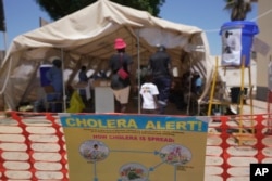 FILE- A family is seen entering a tent set aside for cholera patients at a clinic in Harare, Zimbabwe, Nov. 18, 2023.