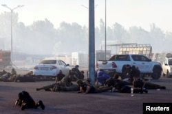 People take cover, after the announcement of a Russian missile attack towards Kharkiv, at the site of a household item shopping mall which was hit by a Russian air strike in Kharkiv, Ukraine, May 25, 2024.