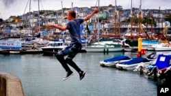 FILE - A young man jumps into the harbor in Brixham, southern England, July 21, 2018.