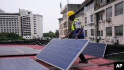 FILE - Oladapo Adekunle, an engineer with Rensource Energy, installs solar panels on a roof of a house in Lagos, Nigeria, March 21, 2024.