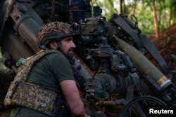 A Ukrainian serviceman prepares to fire a howitzer toward Russian troops near the front line in Donetsk region, Ukraine, May 1, 2024.