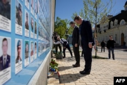British Foreign Secretary David Cameron and Ukrainian Foreign Minister Dmytro Kuleba pay their respects at a memorial wall to fallen servicemen, outside St. Michael's Golden-Domed Monastery in Kyiv, Ukraine, on May 2, 2024.