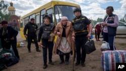 Rescue workers help Liudmila Kalashnik, 88, after evacuation from Vovchansk, Ukraine, May 12, 2024.