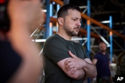 Ukraine's President Volodymyr Zelenskyy looks at damaged to Ukraine's largest printing house, which was hit May 23 in a Russian missile attack that killed seven civilians in Kharkiv, Ukraine, May 24, 2024. (Ukrainian Presidential Press Office via AP)