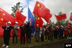 People wave Chinese flags after Chinese President Xi Jinping arrived at Tarbes' airport at the start of his trip to visit the village of Bagnere-de-Bigorre and the adjacent Pyrenees ski resort of La Mongie as part of his state visit to France, May 7, 2024.