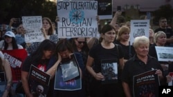 FILE - People hold signs outside the Russian embassy in Kyiv, Ukraine, on July 29, 2023, to mark the anniversary of the explosions at the Russian-controlled prison barracks in Olenivka, eastern Ukraine, which killed dozens of Ukrainian POWs.