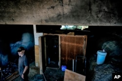 Homeless man Joel Hernandez, 62, stands next to his makeshift home under the 405 Freeway in the Van Nuys section of Los Angeles, July 26, 2024.