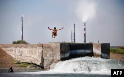 A man jumps into the water of Lake Balkhash in front of Kazakhmys copper smelting plant in the town of Balkhash, Kazakhstan, on June 20, 2024.