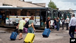 In this photo released by Government of Kursk region of Russia via their telegram channel, Aug. 9, 2024, relatives carry suitcases of their children from the Kursk region helping them to leave on holiday to the Moscow region.