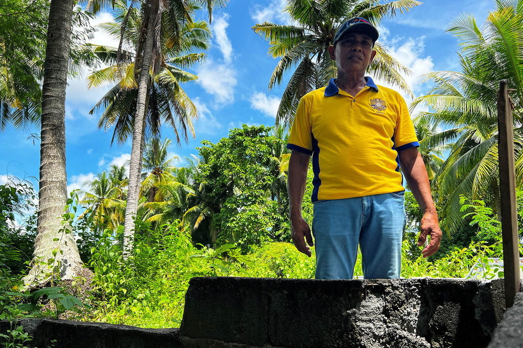 Lumanda "Manny" Idsla stands by the grave of his second cousin whose killing started the feud.