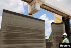 ICON print captain Rogelio Serrano monitors a Vulcan 3D printer printing the walls of a home under construction in Georgetown, Texas, June 26, 2024.