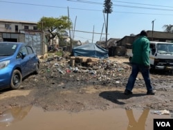 A man walks past sewage that had been in the street for days in Harare's Mbare township on Aug. 12, 2024. (Columbus Mavhunga/VOA)