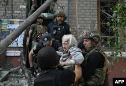 Police officers help a wounded elderly woman out of a damaged building following a Russian strike in Kramatorsk, Ukraine, Sept. 25, 2024.