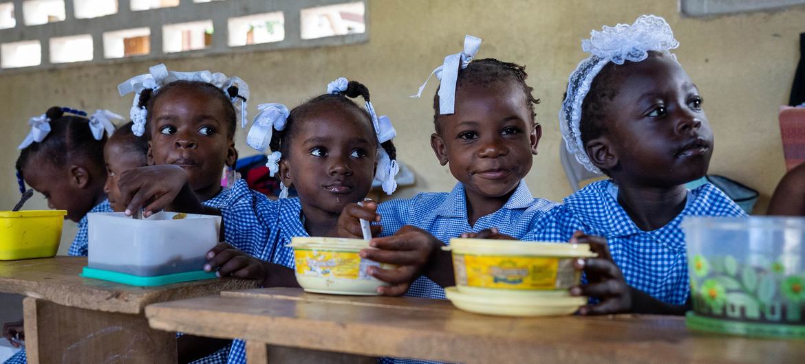 Children in Haiti eat a hot meal provided by the UN and partners at school. 