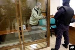 In this photo released by the Moscow City Court Press Service, Stephen Hubbard, a U.S. citizen accused of fighting as a mercenary in Ukraine stands in a glass cage during a court session in Moscow, Oct. 7, 2024.