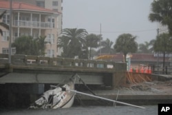 A boat damaged in Hurricane Helene rests against a bridge ahead of the arrival of Hurricane Milton in South Pasadena, Florida, Oct. 9, 2024.