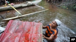 FILE - Paula Hamadi cleans up trash as she collects clams in a mangrove forest where only women are permitted to enter in Jayapura, Papua province, Indonesia, Oct. 2, 2024.