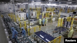 FILE - Workers assemble Photovoltaic Modules at the plant of Adani Green Energy Ltd in Mundra, India, April 11, 2024.