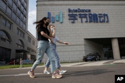 FILE - Women chat as they pass the headquarters of ByteDance, owners of TikTok, in Beijing, China, Aug. 7, 2020.