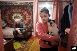 Alina Soboleva, 9, holds her cat "Murchik" at her house in Izium, Ukraine, Dec. 6, 2024.