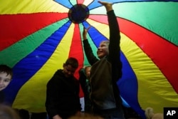 Children stand under a play parachute during an event organized by the local NGO Ukrainian Frontiers during celebration St. Nicholas Day in Izium, Ukraine, Dec. 6, 2024.