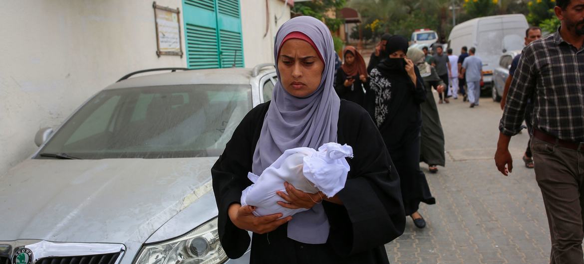 A woman carries the body of a newborn killed in an attack on Nasser Hospital in Khan Younis, Gaza.